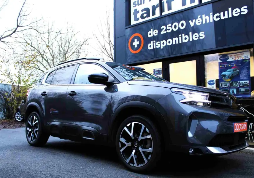 Citroën C5 Aircross gris platinium en 3/4 avant droit, avec jantes noires et argent et phares allumés.