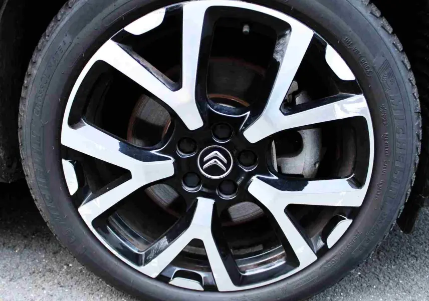 Gros plan sur la jante alliage bicolore noire et argent avec logo Citroën au centre, roue du C5 Aircross gris platinium.