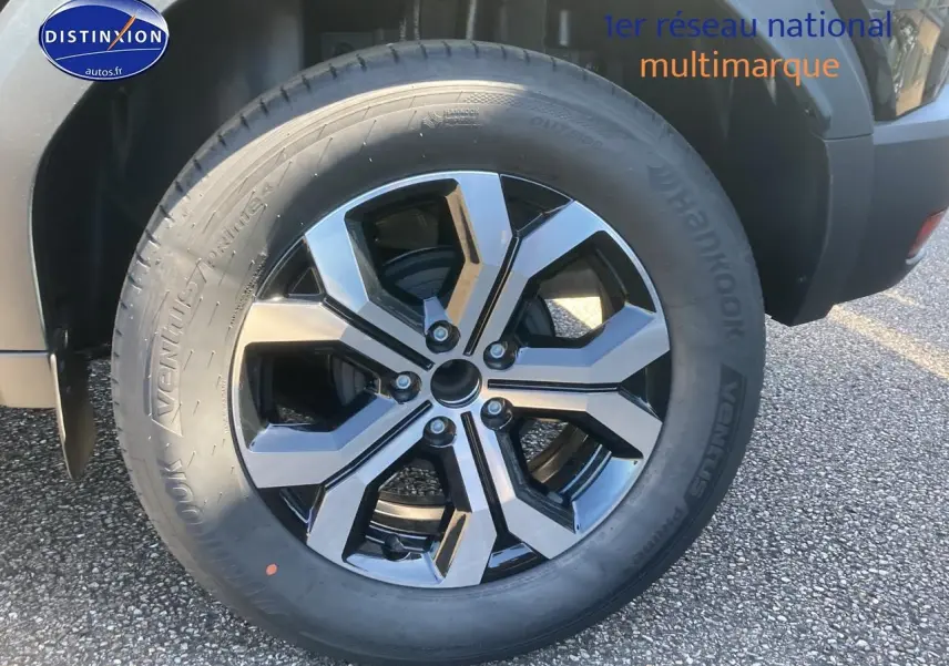 Gros plan sur la jante alu noire et argent du côté droit du Dacia Duster noir 2025.