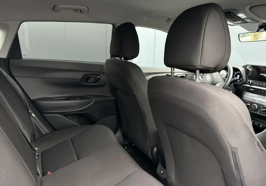 Vue intérieure arrière de la Hyundai i20 2025 avec sièges tissu noirs et tableau de bord visible côté droit.