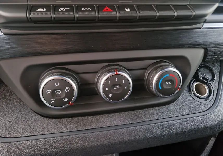Gros plan sur les commandes de climatisation et ventilation du tableau de bord du Nissan Primastar gris urbain 2025.