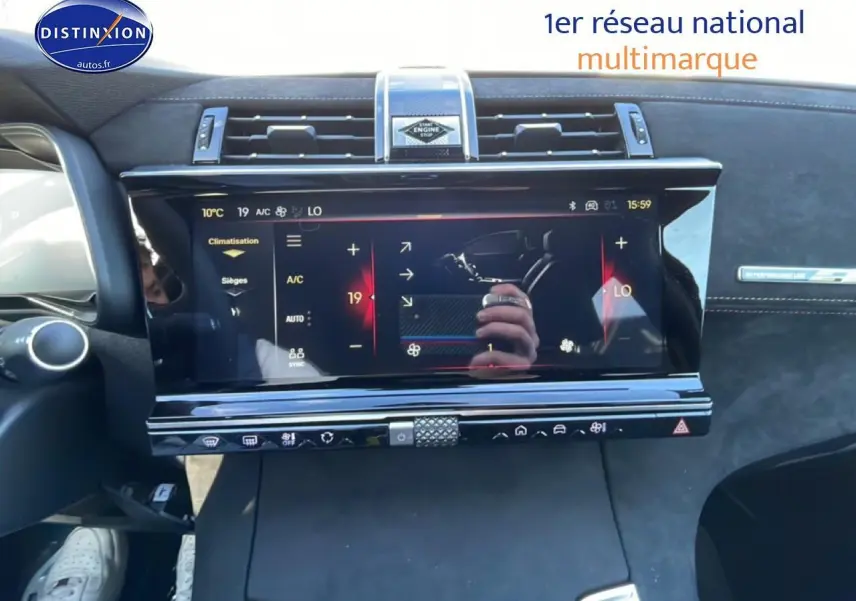 Vue rapprochée de l'écran tactile central noir du tableau de bord du DS7 bleu, avec commandes climatisation visibles.