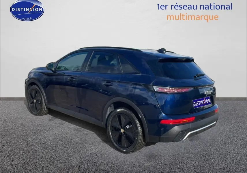 Vue 3/4 arrière droite d'un DS7 bleu foncé avec jantes noires et vitres arrière surteintées sur fond neutre.