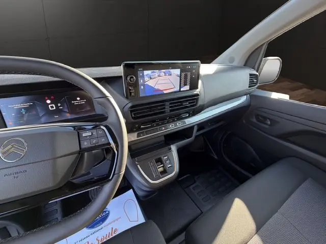Vue intérieure côté conducteur du Citroën Jumpy gris titane, avec tableau de bord numérique et écran de caméra de recul.