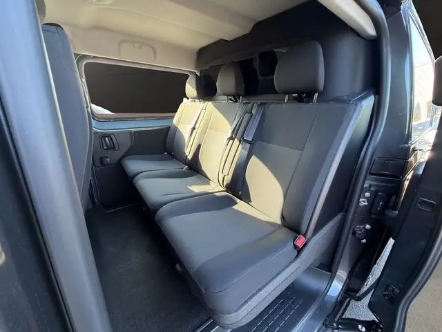 Vue intérieure de la banquette arrière 3 places du Citroën Jumpy gris titane, côté droit avec porte ouverte.