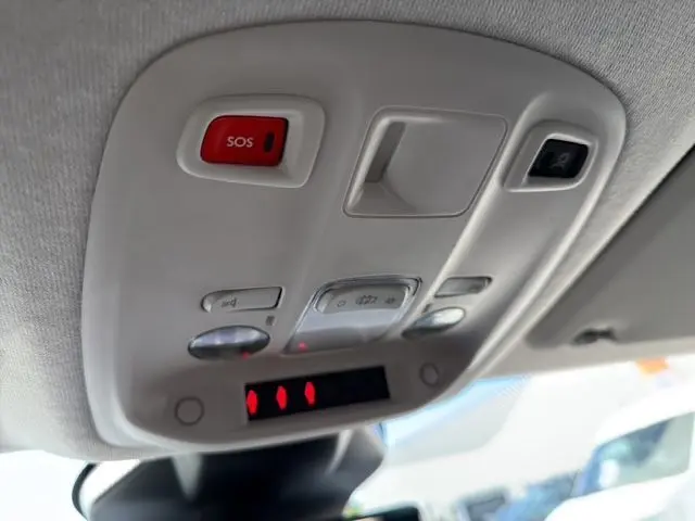Vue en gros plan du plafonnier intérieur gris clair du Citroën Jumpy avec bouton SOS rouge et commandes d'éclairage.