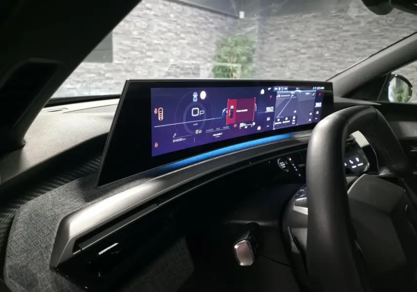 Vue intérieure du tableau de bord du Peugeot 5008 noir 2025, avec écran panoramique HD et volant compact noir laqué.