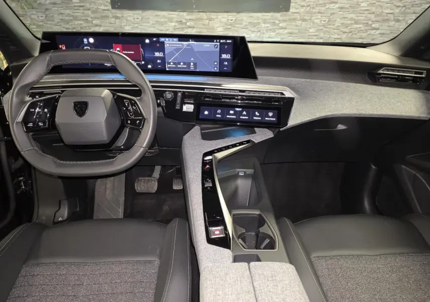 Vue intérieure avant du Peugeot 5008 2025 hybride, tableau de bord moderne avec double écran HD et volant compact cuir noir.