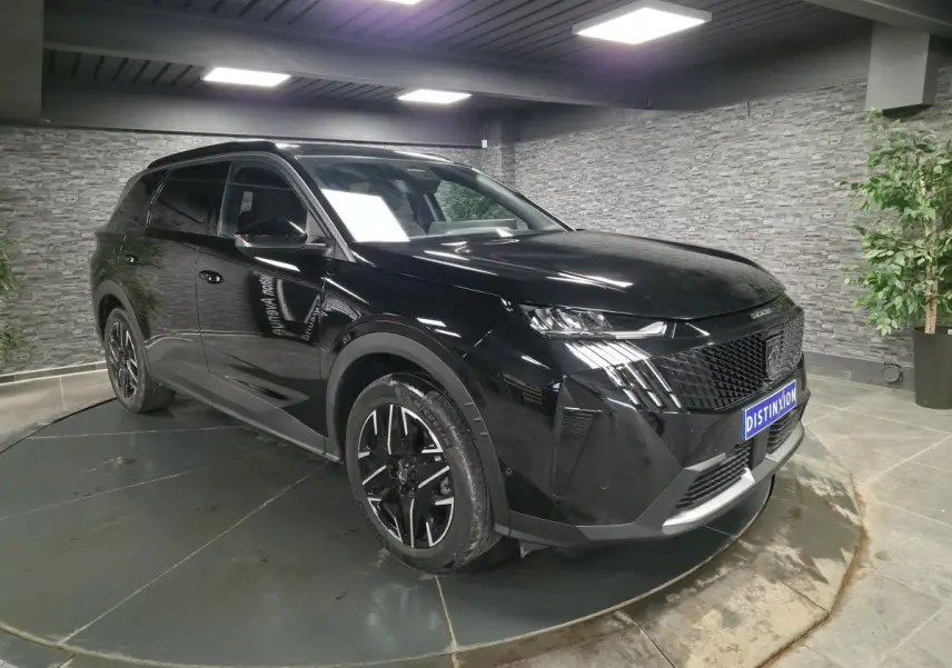 Peugeot 5008 noir vue 3/4 avant droit en intérieur, avec jantes alliage 19'' et calandre noire distinctive.