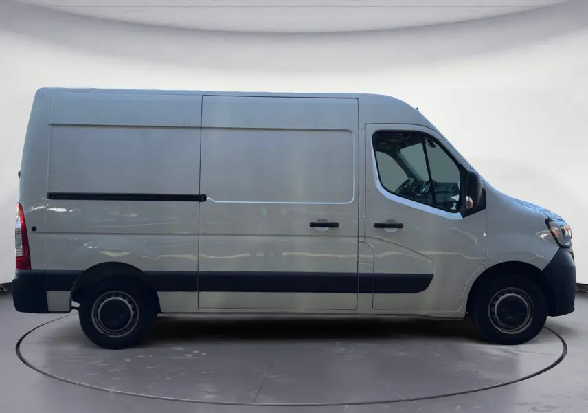 Profil droit d’un utilitaire blanc Renault Master L2H2 2024 avec porte coulissante et protections noires sur les bas de caisse.