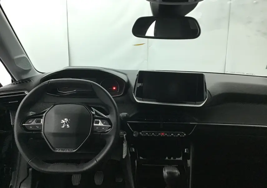 Vue intérieure du tableau de bord noir de la Peugeot 208 2022 avec volant compact et écran tactile central.