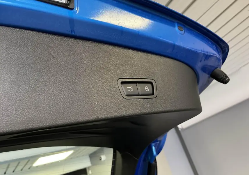 Bouton de fermeture électrique du hayon sur la partie intérieure du coffre bleu d'une Alfa Romeo Tonale 2024.