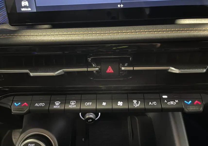 Gros plan sur la console centrale de l'Alfa Romeo Tonale bleu 2024, mettant en valeur les commandes de climatisation et le bouton de warning.