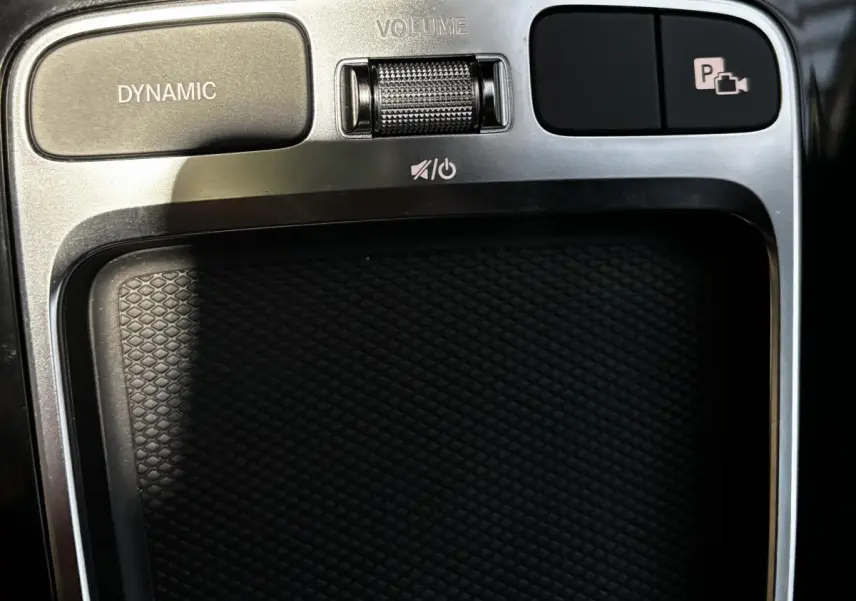 Gros plan sur la console centrale argentée et noire du Mercedes CLA 250 e AMG Line avec boutons Dynamic et contrôle volume.
