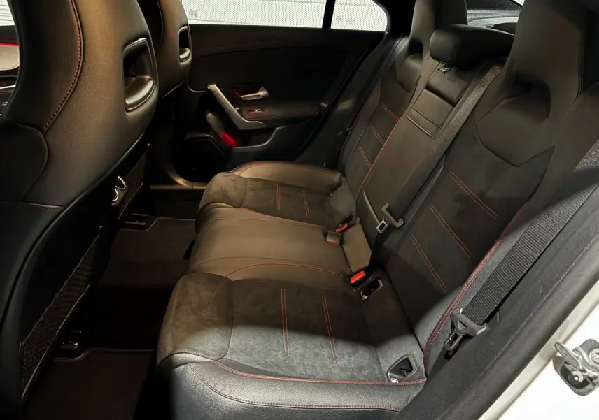 Vue intérieure côté droit des sièges arrière noirs avec surpiqûres rouges dans une Mercedes CLA 250 e AMG Line blanche 2023.