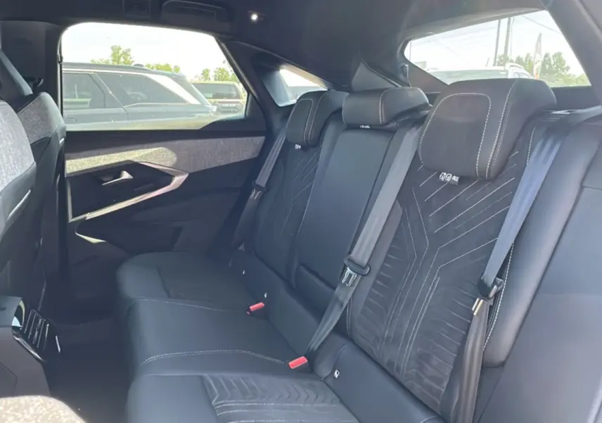 Vue intérieure arrière du Peugeot 3008 Hybrid 145 GT Alcantara avec sellerie cuir noir et inserts tissu gris.