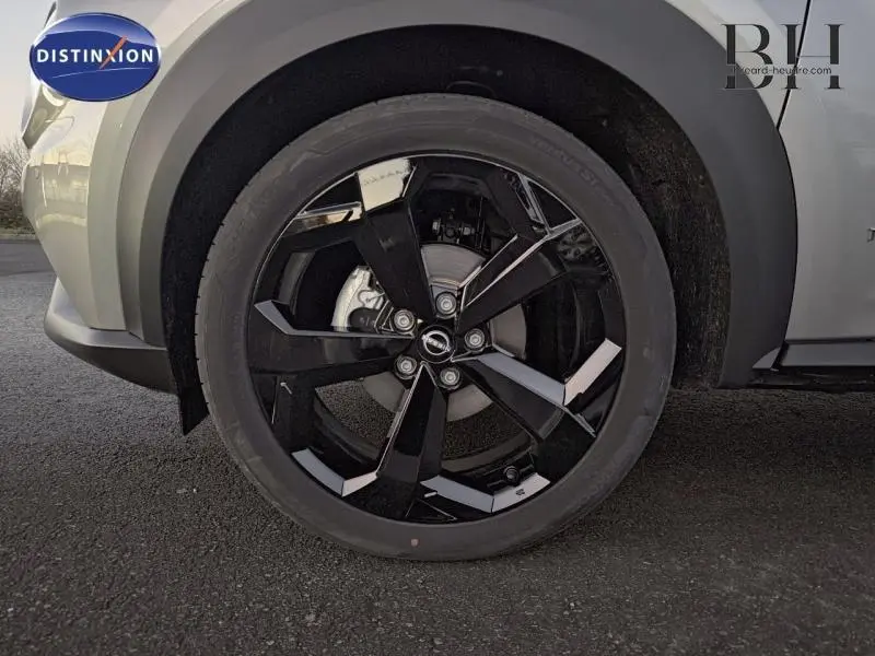 Gros plan sur la roue avant droite du Nissan Juke 2025 gris perle métallisé, mettant en valeur la jante noire au design moderne.