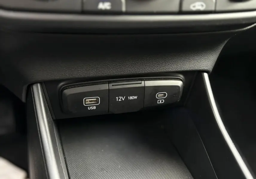 Gros plan sur la console centrale de la Hyundai i20 2025, montrant les ports USB et prise 12V noirs.
