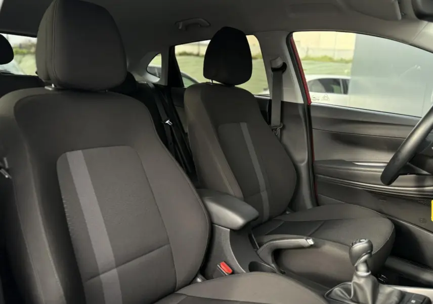 Vue intérieure côté droit montrant les sièges avant noirs et la console centrale d'une Hyundai i20 Rouge Dragon Metal 2025.