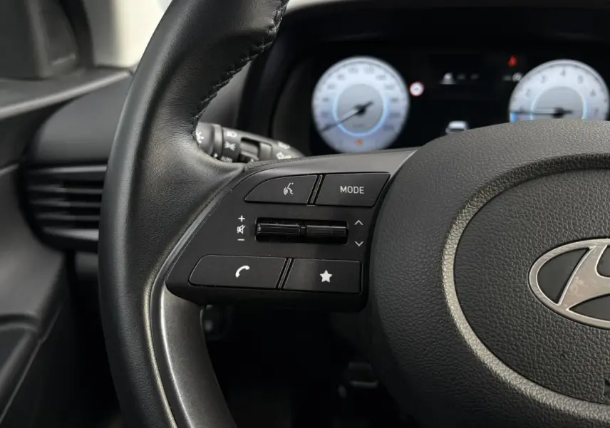 Gros plan sur le volant multifonction noir de la Hyundai i20 2025 avec commandes audio et téléphone intégrées.