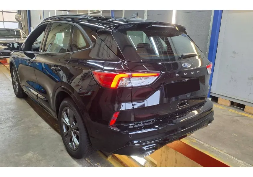 Vue 3/4 arrière droite du Ford Kuga noir Agathe avec feux allumés et crochet d'attelage amovible visible.