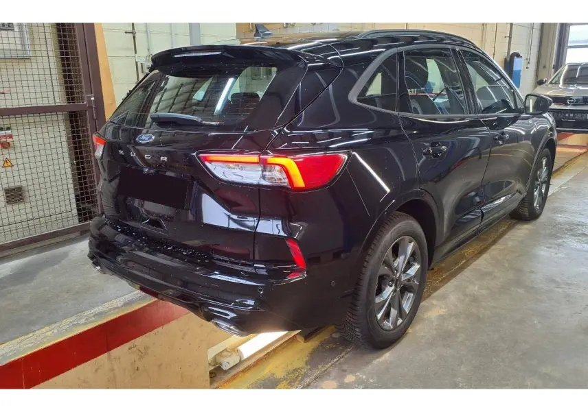 Vue 3/4 arrière droite du Ford Kuga 2024 noir Agathe avec feux LED et double sortie d’échappement ST-Line visible.