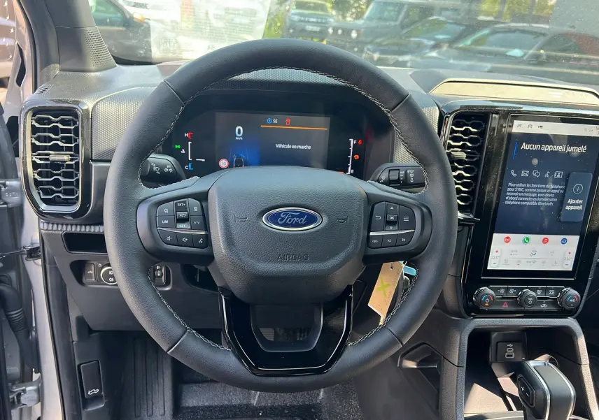Vue intérieure centrée sur le volant cuir multifonctions du Ford Ranger 2025 avec écran tactile et tableau de bord numérique.