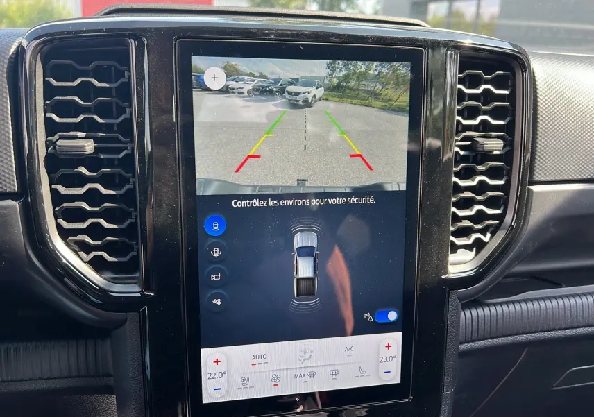 Écran central du Ford Ranger 2025 montrant la caméra de recul et les capteurs de stationnement, intérieur noir.