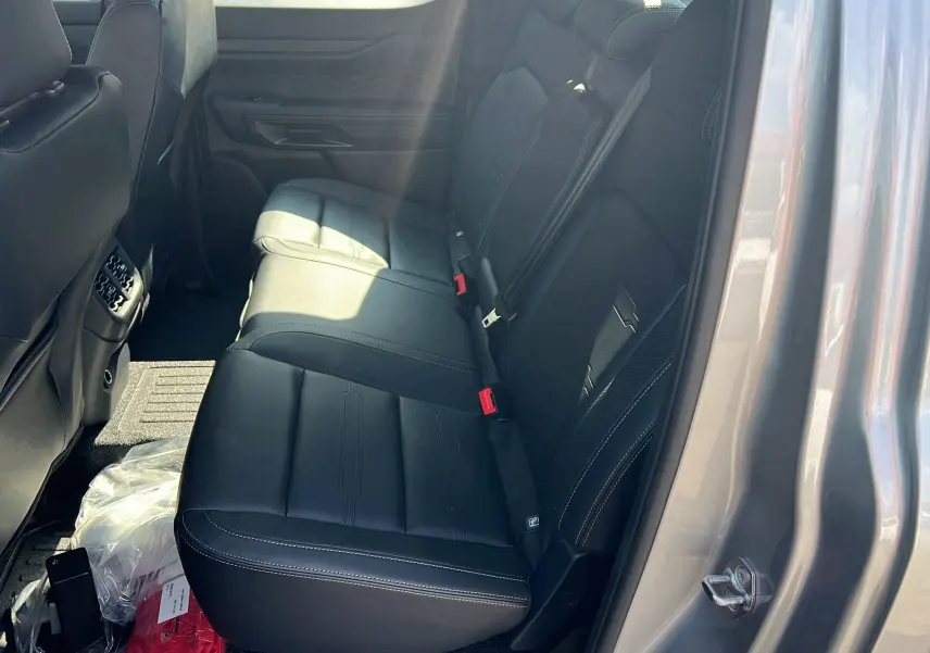 Vue intérieure arrière droite du Ford Ranger 2025 gris iconic, montrant les sièges en cuir noir avec surpiqûres blanches.