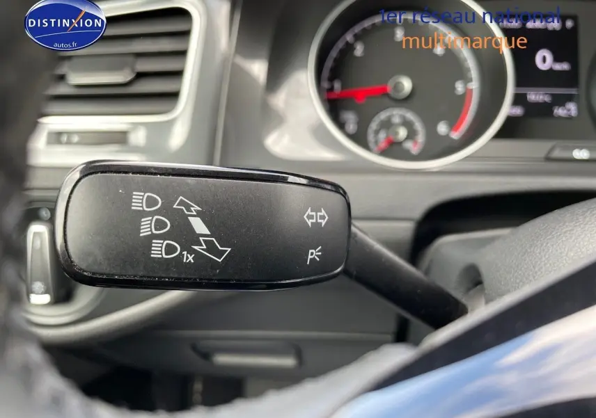 Gros plan sur la manette de clignotant à gauche du volant dans l’habitacle d’une Volkswagen Golf rouge de 2018.