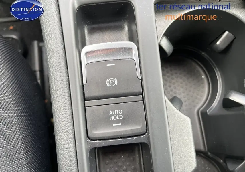 Gros plan sur la console centrale de la Volkswagen Golf rouge, montrant les boutons frein à main électronique et auto hold.