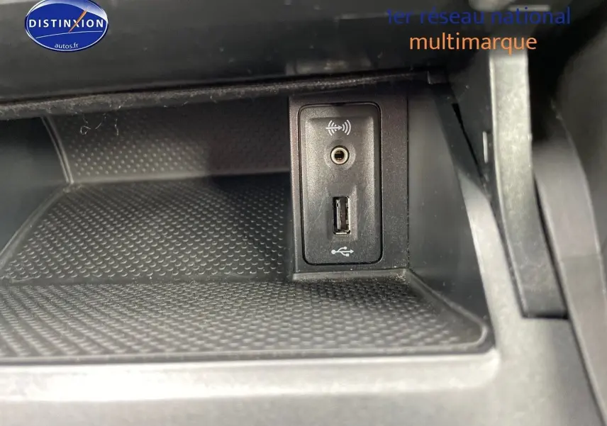 Vue rapprochée de la prise USB et jack audio dans le compartiment intérieur noir d'une Volkswagen Golf VII rouge.