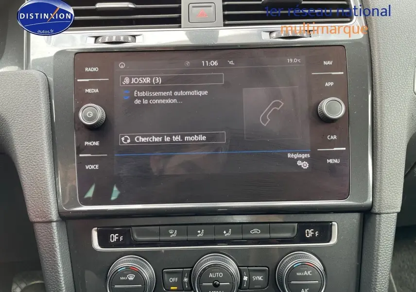 Vue rapprochée de la console centrale de la Volkswagen Golf VII rouge, affichant l’écran multimédia et les commandes de climatisation.