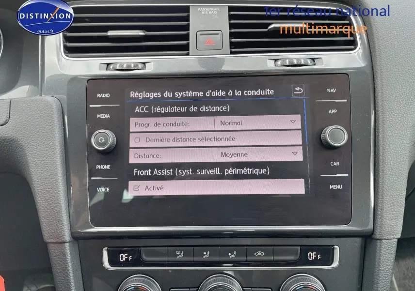Vue rapprochée de l’écran tactile central et de la console de la Volkswagen Golf VII rouge, affichant les réglages d’aide à la conduite.