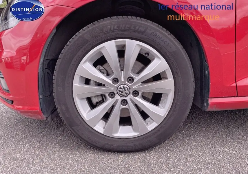 Gros plan sur la roue avant gauche d'une Volkswagen Golf rouge, mettant en valeur la jante alliage et le pneu Michelin.