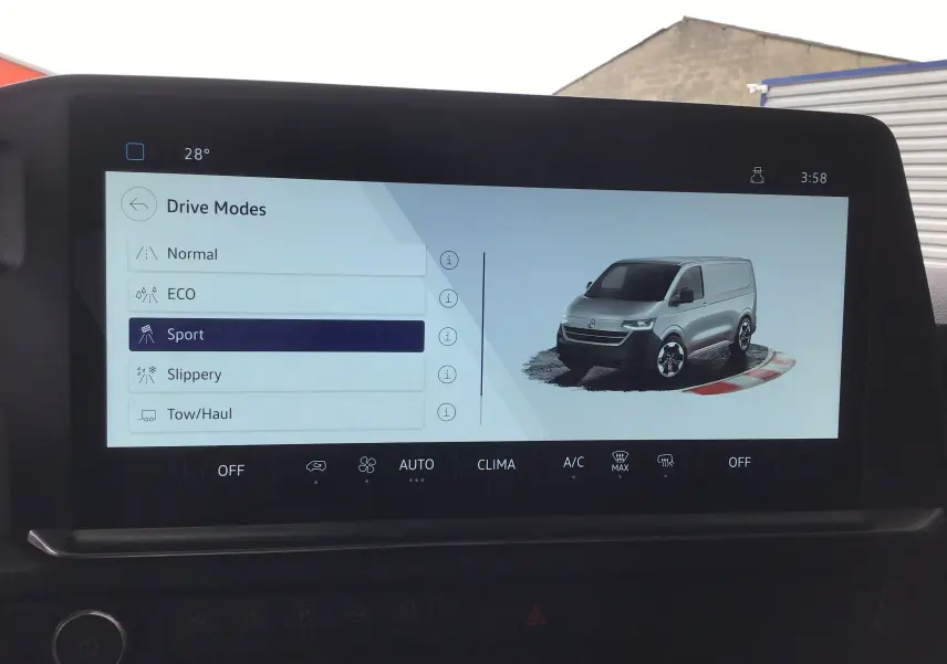 Écran central montrant un Volkswagen Transporter T7 gris anthracite en vue 3/4 avant avec mode de conduite Sport sélectionné.