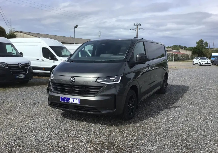 Vue 3/4 avant d'un Volkswagen Transporter T7 gris anthracite avec projecteurs LED Matrix et barres de toit repliables.