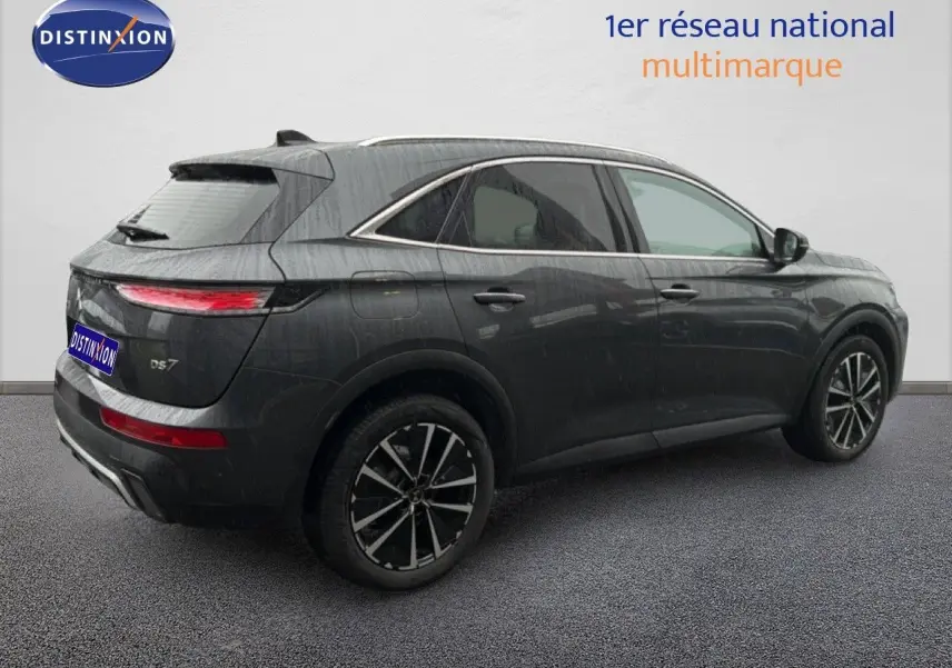 Vue 3/4 arrière droite d'un DS7 gris titane métal 2024 avec jantes noires bicolores et feux arrière LED fins.