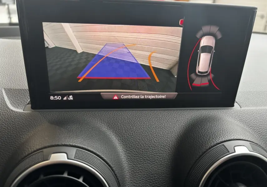 Écran central de l'Audi Q2 noir 2023 montrant l'aide au stationnement avec caméra arrière et guidage de trajectoire.