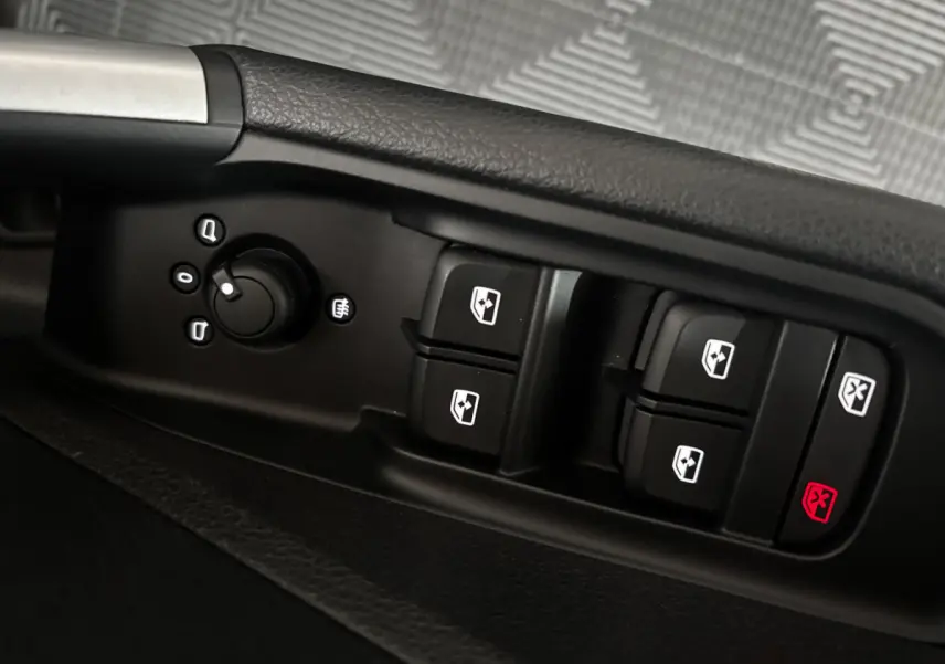 Gros plan sur les commandes de lève-vitres et réglage des rétroviseurs côté conducteur d’un Audi Q2 noir 2023.