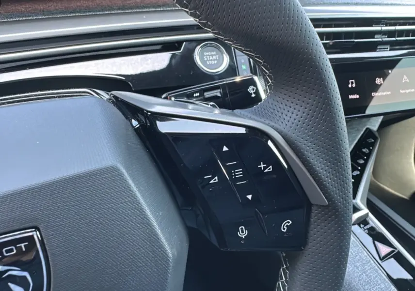Vue rapprochée du volant cuir perforé de la Peugeot 3008 Hybrid 145 GT avec commandes multifonctions et bouton start/stop.