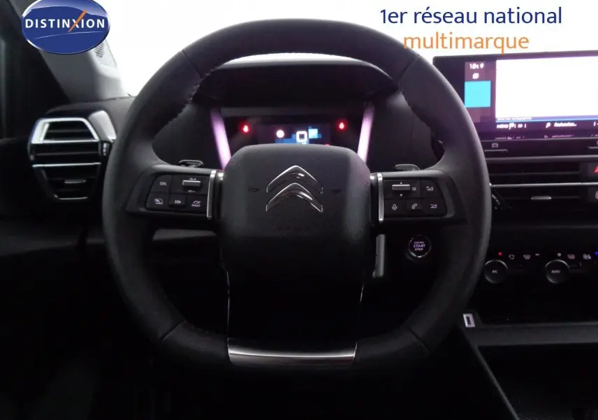 Vue rapprochée du volant multifonction noir de la Citroën C4 2023 avec tableau de bord digital et écran tactile.
