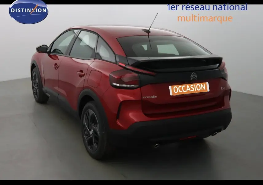 Vue 3/4 arrière droite d'une Citroën C4 rouge Elixir métal avec toit noir et jantes noires en studio.