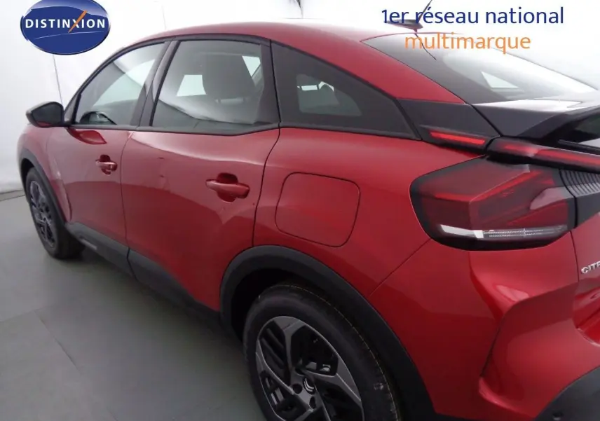 Vue 3/4 arrière gauche d'une Citroën C4 rouge Elixir métal avec toit noir et jantes alliage bicolores.