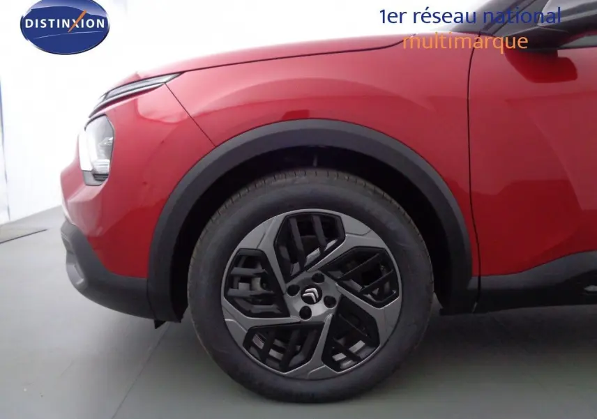 Gros plan sur la roue avant gauche d'une Citroën C4 rouge Elixir Métal avec jante alliage noire et grise.