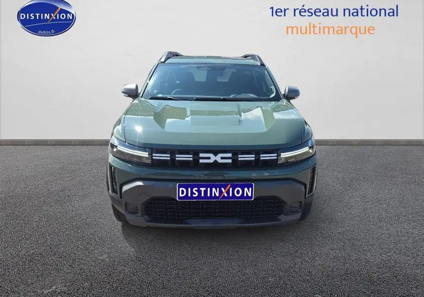 Vue avant du Dacia Duster 2025 vert kaki avec calandre noire et barres de toit visibles.