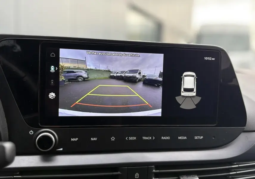 Écran tactile intérieur montrant la caméra de recul et l’aide au stationnement du Hyundai i20 blanc Atlas.