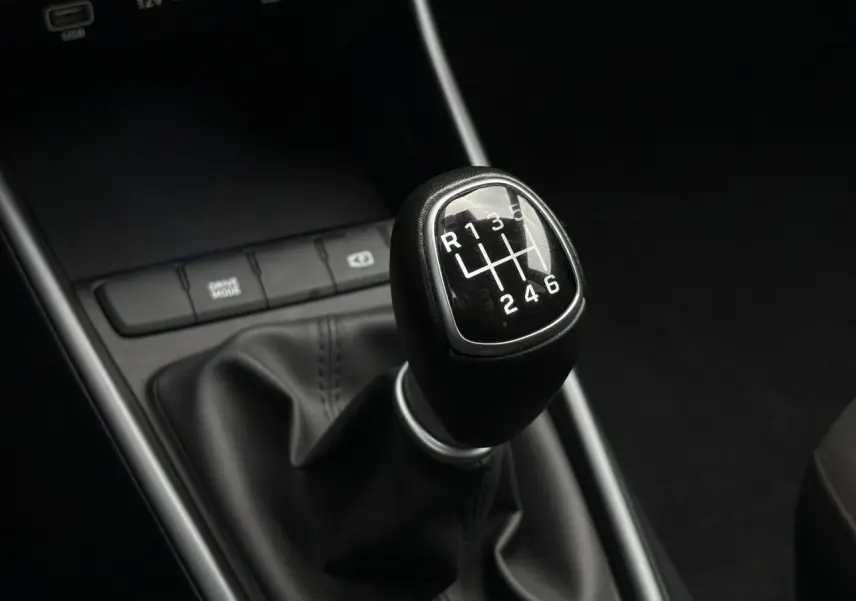 Gros plan sur le levier de vitesses manuel noir de la Hyundai i20 2025, entouré de la console centrale noire.