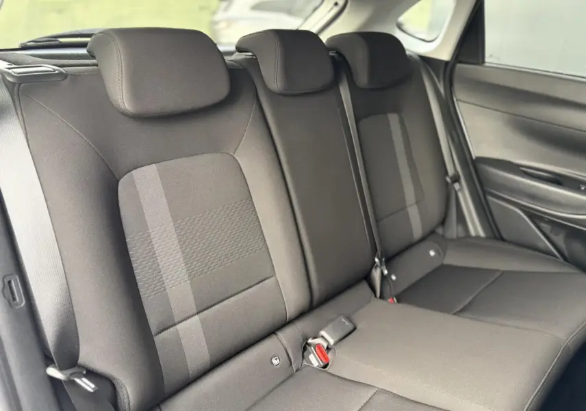 Vue intérieure côté droit des sièges arrière noirs de la Hyundai i20 2025 avec appuie-têtes et ceintures visibles.