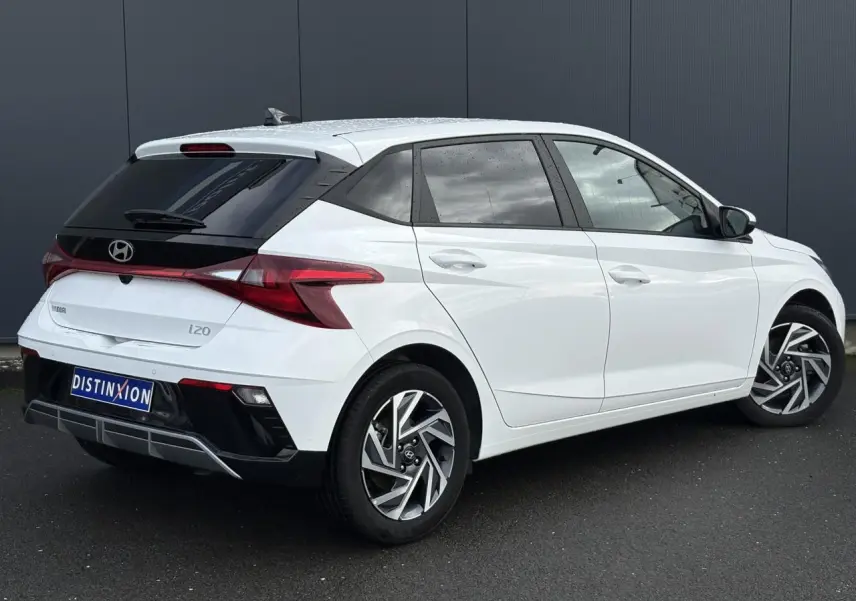 Vue 3/4 arrière droite d'une Hyundai i20 blanche Atlas avec jantes alliage et vitres arrière surteintées.